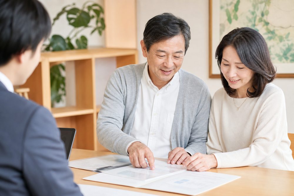 50代夫婦が明るい相談デスクで老後資金の書類を確認している様子