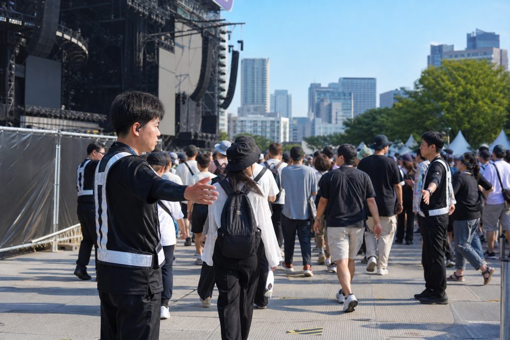 東京の野外音楽フェスで警備スタッフが観客を整然と誘導している様子