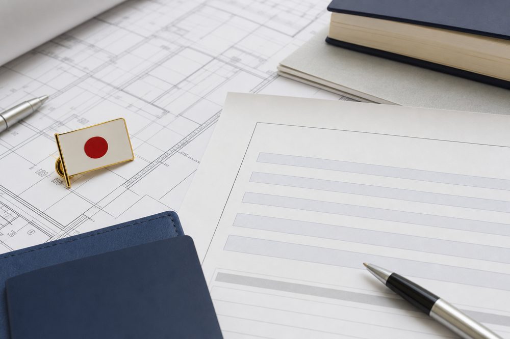 在留資格申請書類と建設図面が並ぶ机の様子