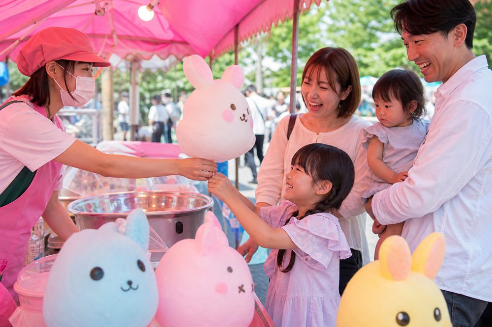 キャラクターわたあめブースで笑顔の子どもたちと親に手渡されるカラフルなわたあめ