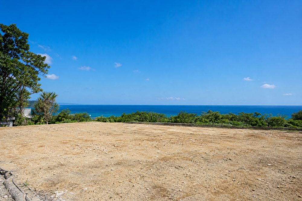 解体後に更地となった沖縄の土地と青い空と海の景色