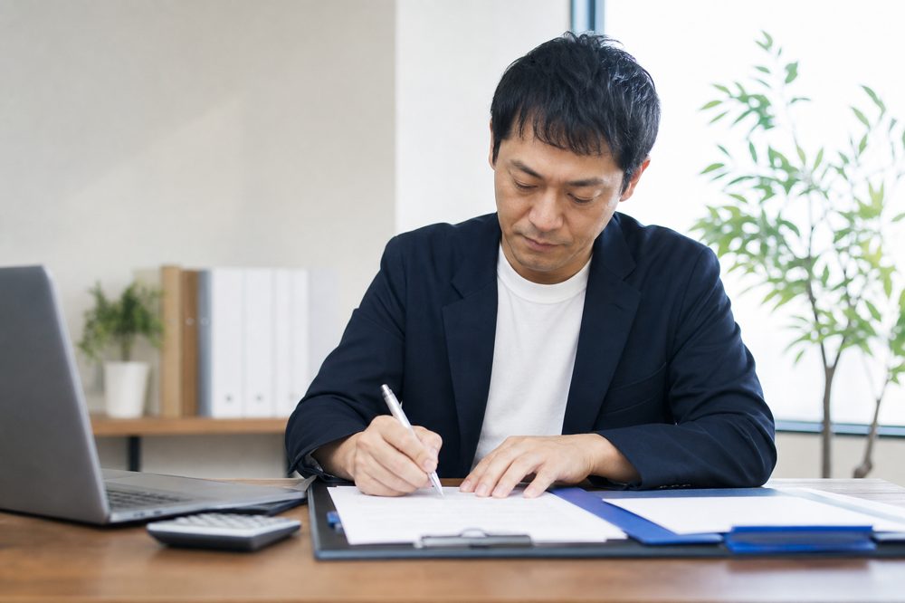 中小企業の経営者が補助金申請書類に記入している様子