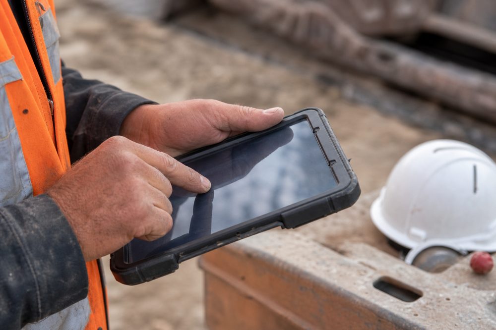 建設現場で防塵タブレットにデータ入力する作業員の手元