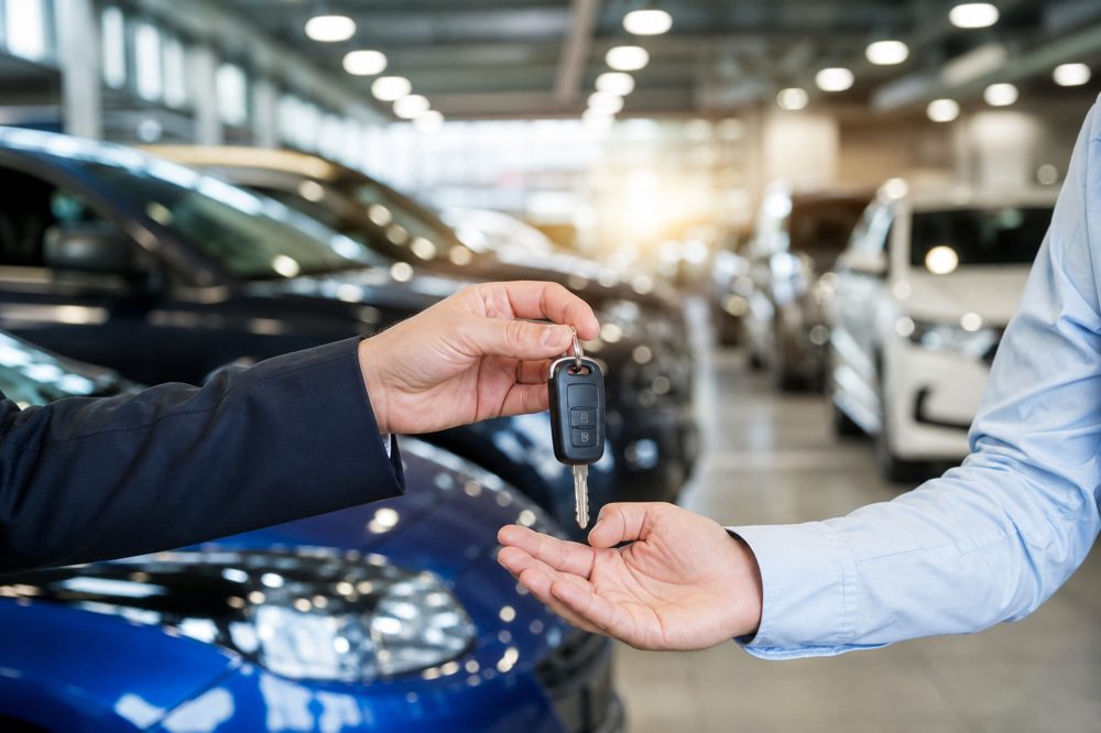 車買取業者オークション代行のイメージ：駐車場に並んだ車と鍵を受け渡すシーン