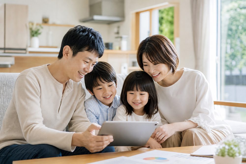 子育て世帯が家族でタブレットを見ながら将来の教育資金計画を確認している様子