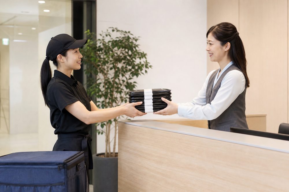 会議弁当を会社の受付に届けるスタッフのイメージ