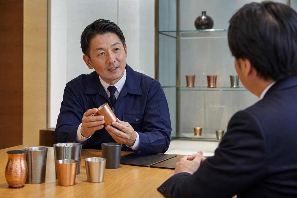 関西の中小製造業の創業者が百貨店バイヤーに商品をプレゼンする商談シーン