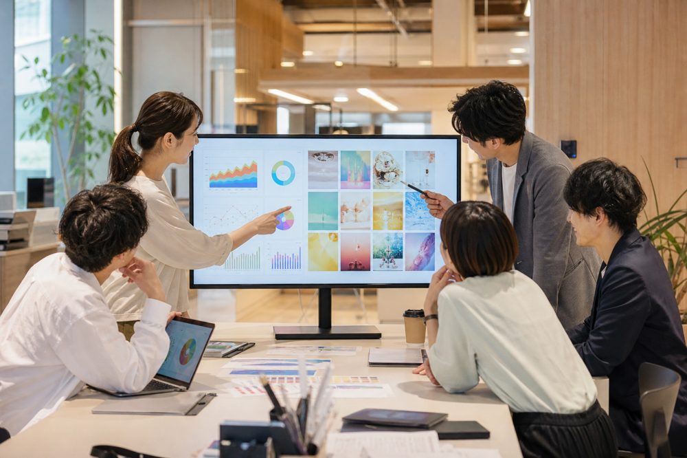 SNS運用チームがデータ分析と投稿計画について話し合っている様子