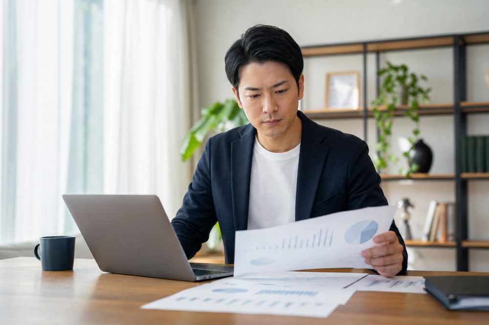 自宅で資産運用の書類を確認するビジネスパーソンのイメージ