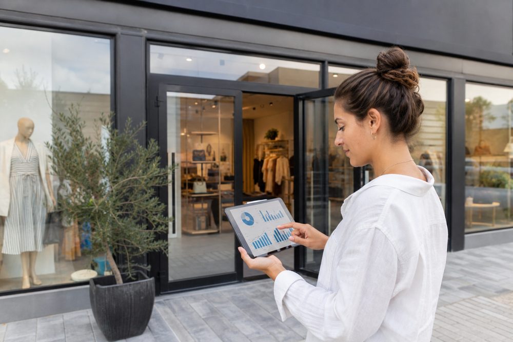 店舗外で看板の効果データをタブレットで分析している店舗オーナー