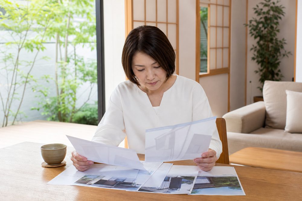 日本の明るいリビングでエコキュート交換の複数見積もりを比較する住宅オーナー