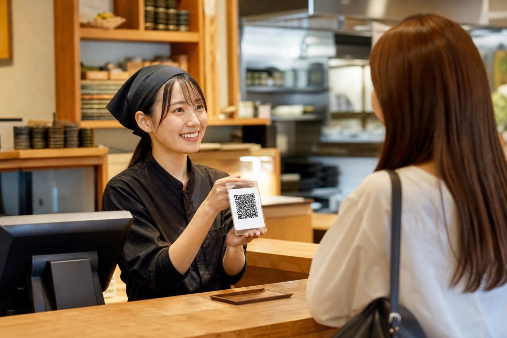 飲食店スタッフがお客様にLINE登録のQRコードを案内している様子