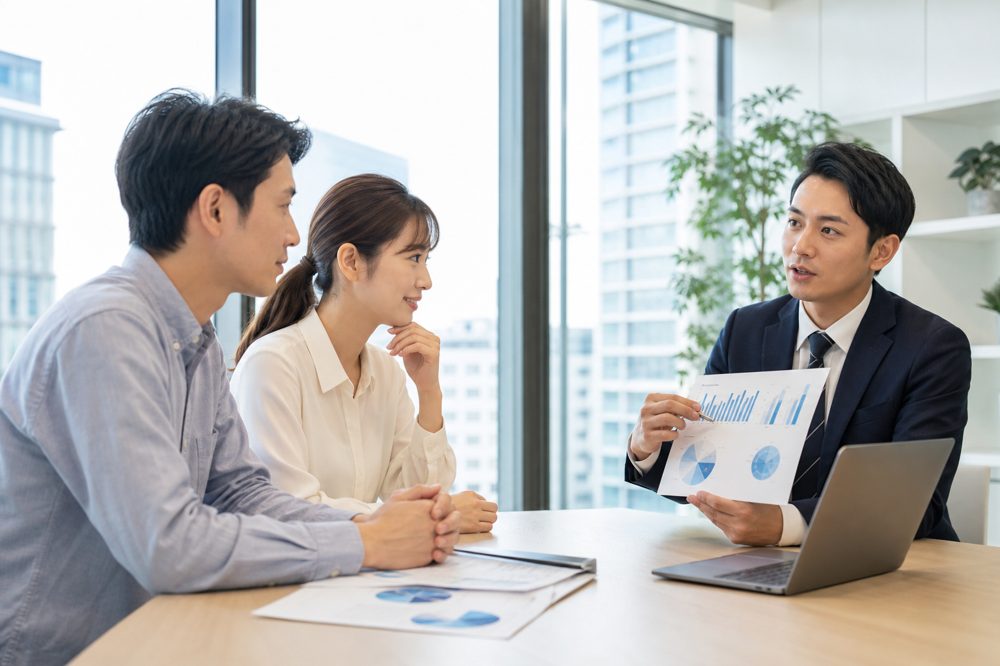 福岡のオフィスでFPが若いカップルに投資の説明をしている