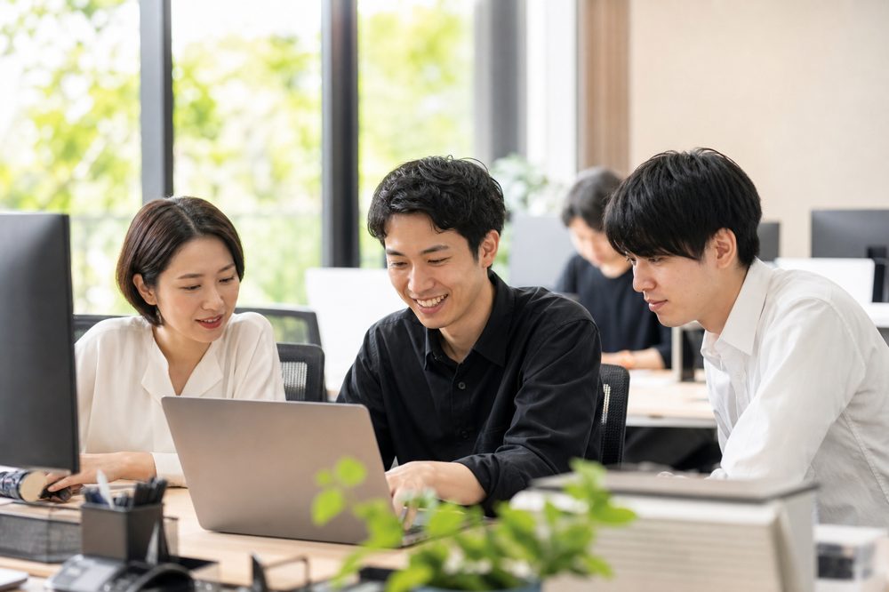 ベトナム人エンジニアが日本のオフィスで日本人同僚と協力して働いている様子