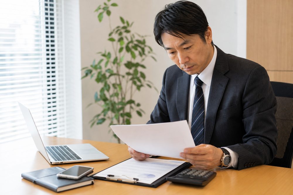 法人携帯の契約書を慎重に確認するビジネスマネージャー