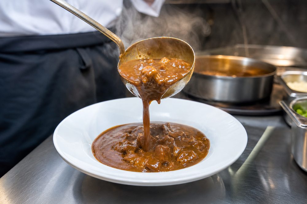 業務用カレーを飲食店のプロキッチンで盛り付けているシーン