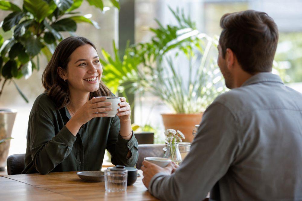 植物のある明るいカフェで気軽に会話を楽しむ男女