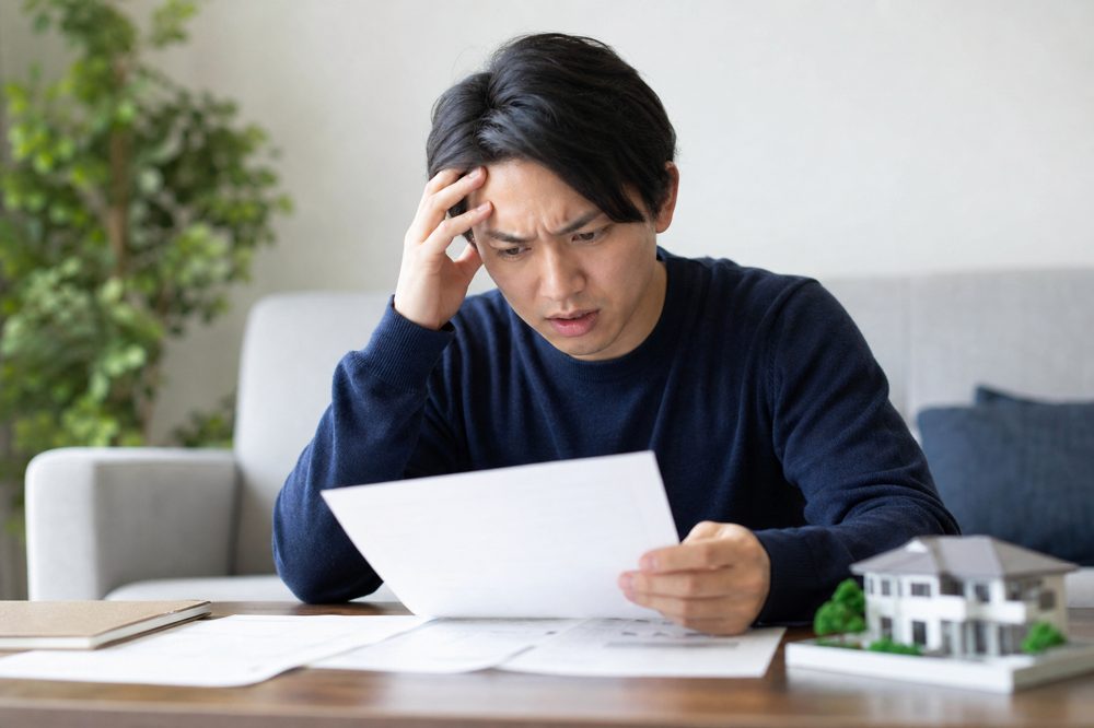 不動産書類を見て悩む日本人の売主イメージ