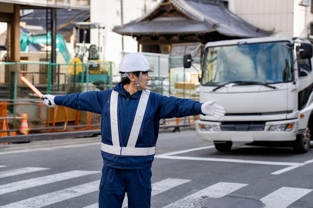 京都の工事現場で車両を誘導する交通誘導警備員