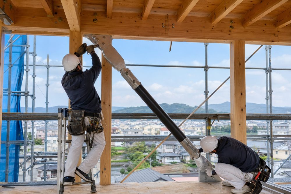 福山市の注文住宅建設現場で制震ダンパーを設置する様子
