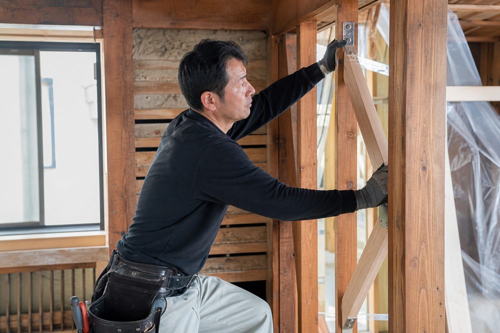 戸建て住宅の壁内部に耐震補強（筋交い）を施工する大工職人