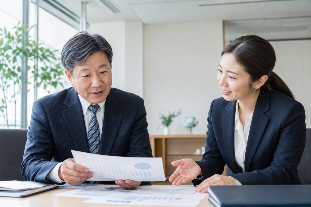 日本の介護施設の管理者が人材紹介会社のコンサルタントと採用費用の書類を確認している様子