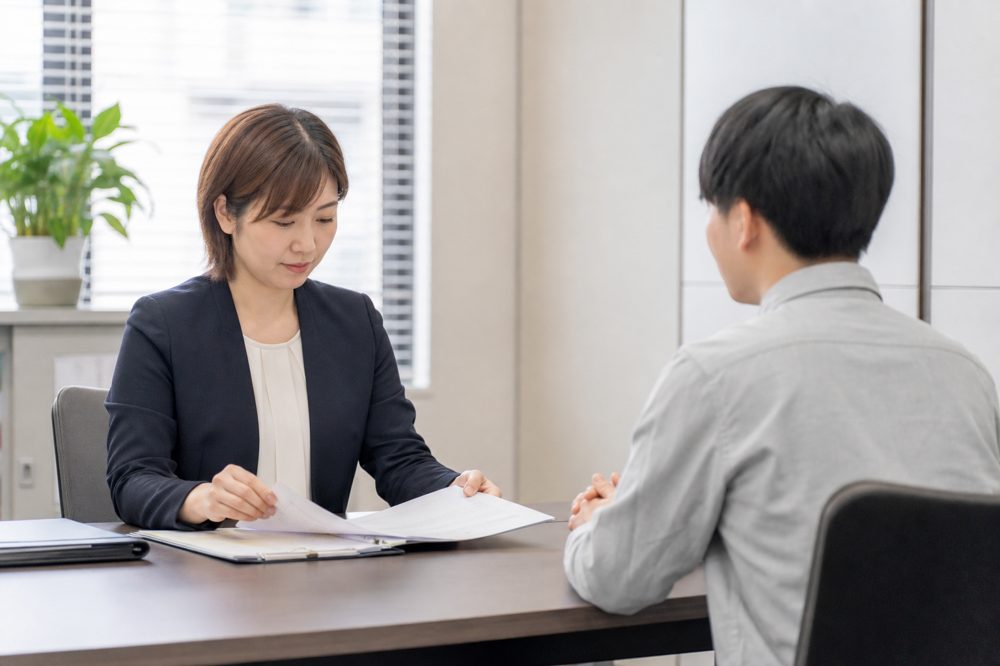 日本人人事担当者が外国人労働者と書類を確認している場面