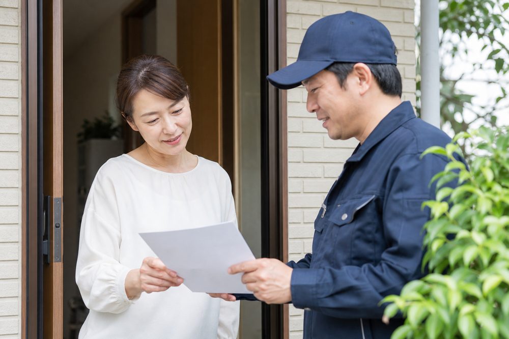 自宅玄関で剪定業者と見積書を確認している様子