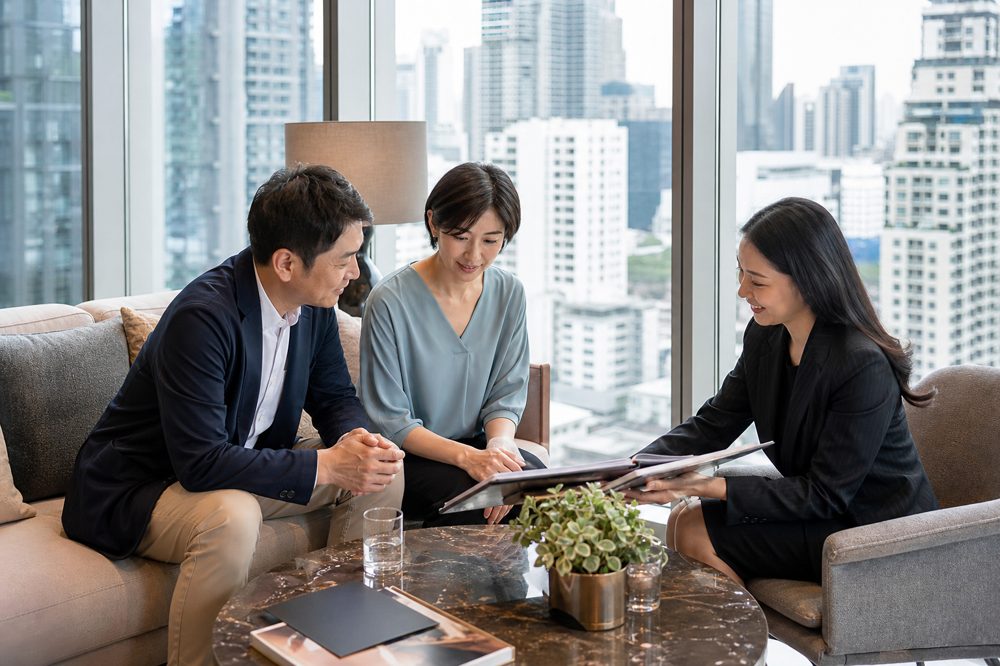バンコクのコンドミニアムショールームで日本人投資家と現地仲介業者が物件について話し合う場面