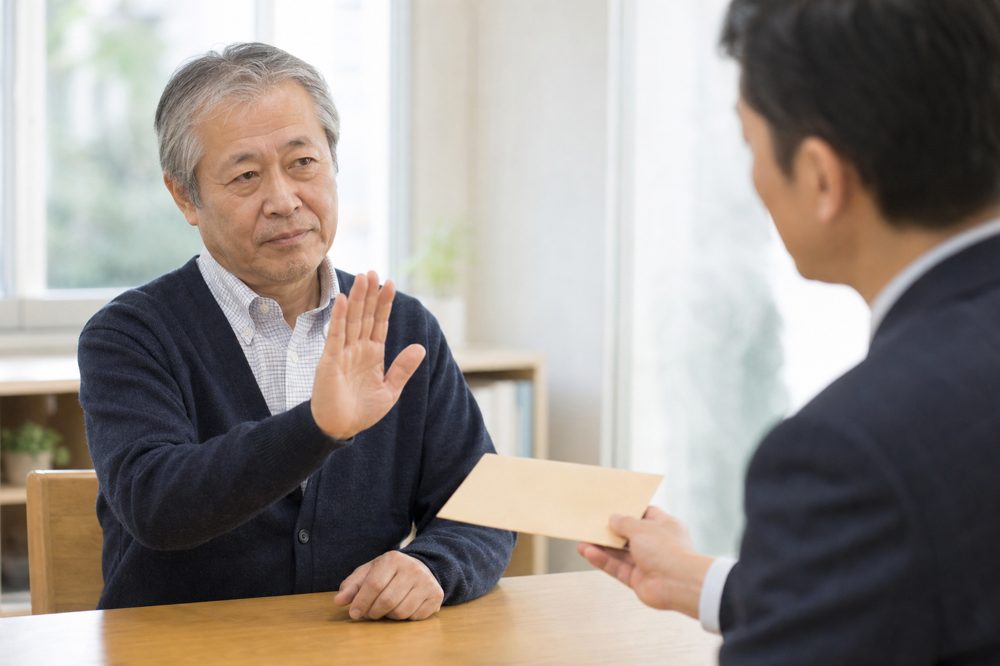 60代男性が不審な金融商品の勧誘を冷静に断っているイメージ