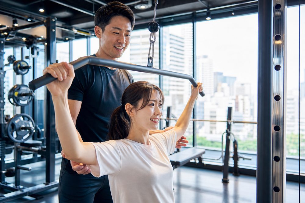 大阪の明るいパーソナルジムでトレーナーが会社員を指導している様子